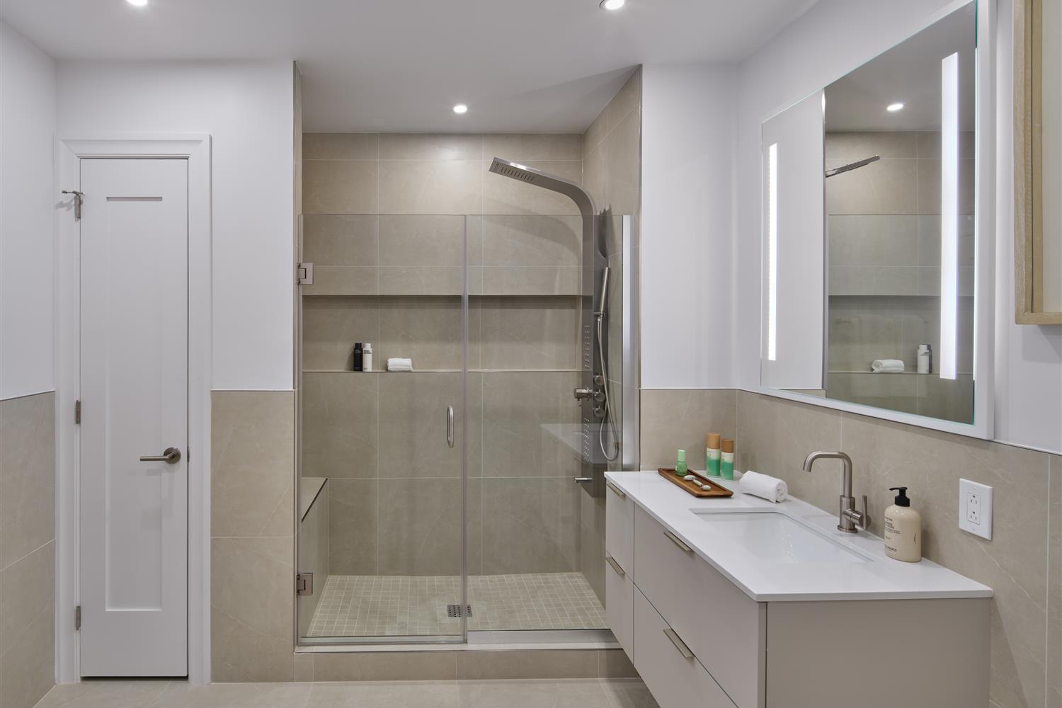Bathroom with large vanity and a shower with a stone seat and a moveable shower head